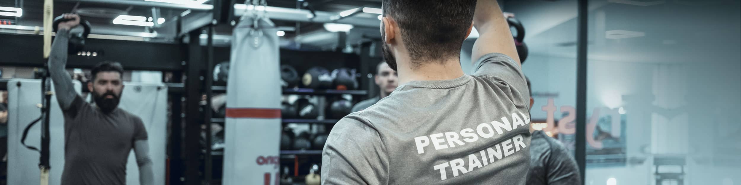 Personal Trainer supporting men working out in a gym